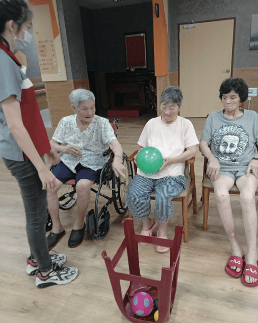 屏東大愛護理之家以「預防延緩」做為照顧主軸的核心，工作人員陪長輩玩投球復健。（圖片來源／屏東大愛護理之家）
