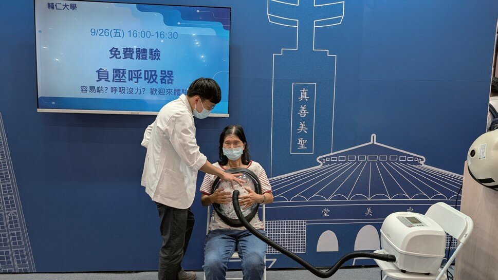 輔大加速器的輔導企業玖顧醫材，協助民眾體驗肺功能復原利器「肺盈負壓呼吸器」，新推出的透明胸甲可觀察到胸部起伏狀況。(圖片來源/輔仁大學)
