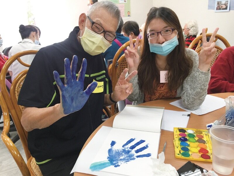 大學生陪伴年長者一起整理人生故事並進行創作，以手印家庭樹描繪原生家庭。(圖片來源/新活藝術)
