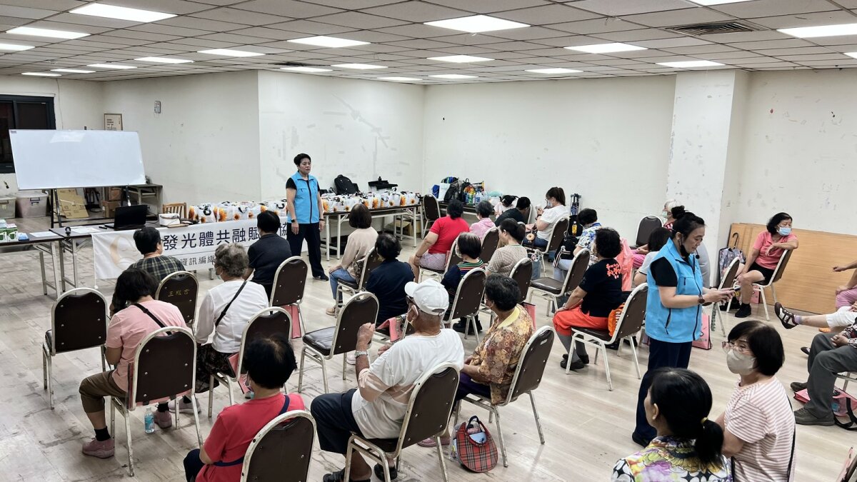 長者在室內活動空間圍坐，參與工作人員帶領的團體活動